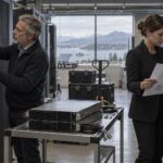 Un técnico revisa conexiones de servidores mientras una directiva consulta un esquema de migración.
